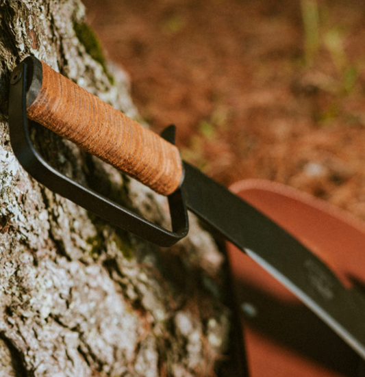 Close-up of a Woodman’s Pal machete showing the leather handle and blade used for wood clearing. 