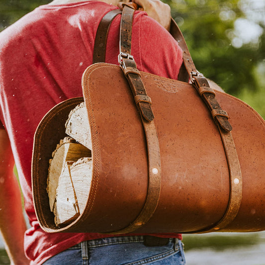 A person carrying the Woodman's Pal Leather Log Carrier over their shoulder