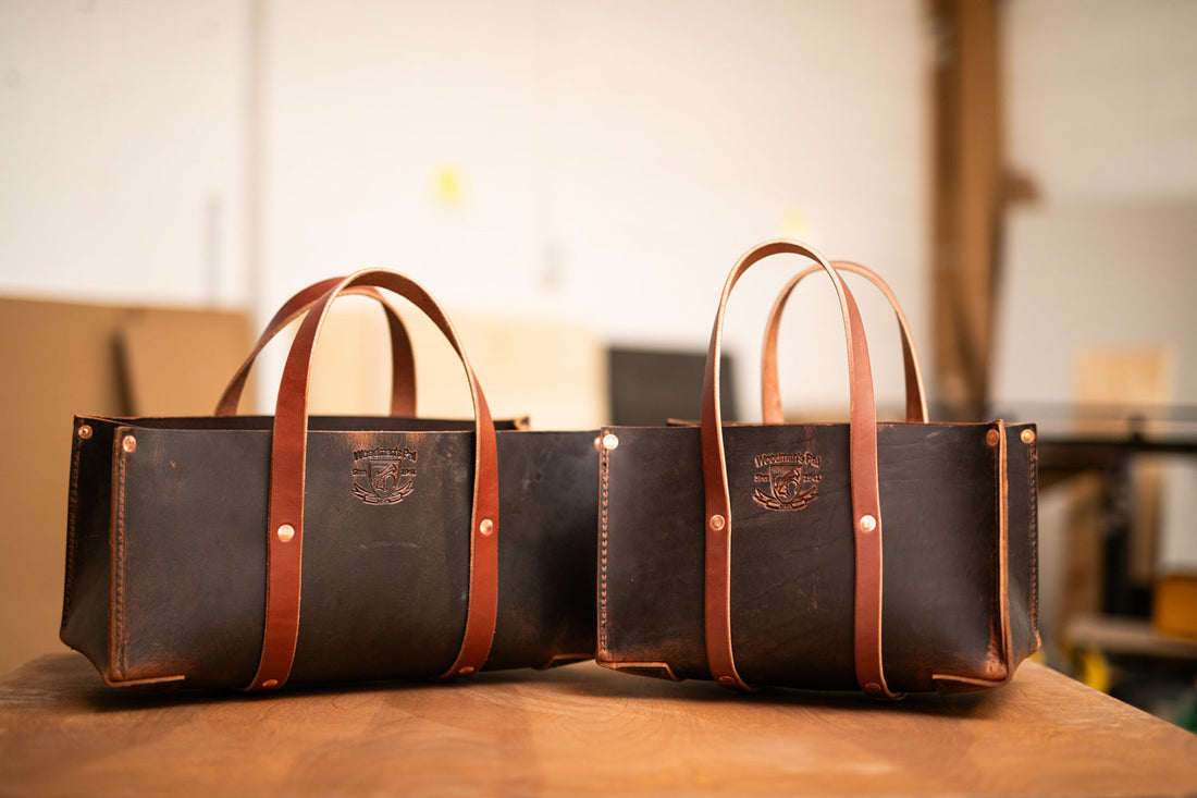 Woodman’s Pal leather tool bag totes in two sizes on a wooden table, showing the rugged design and sturdy handles that make this garden tool tote bag ideal for organizing gardening tools.