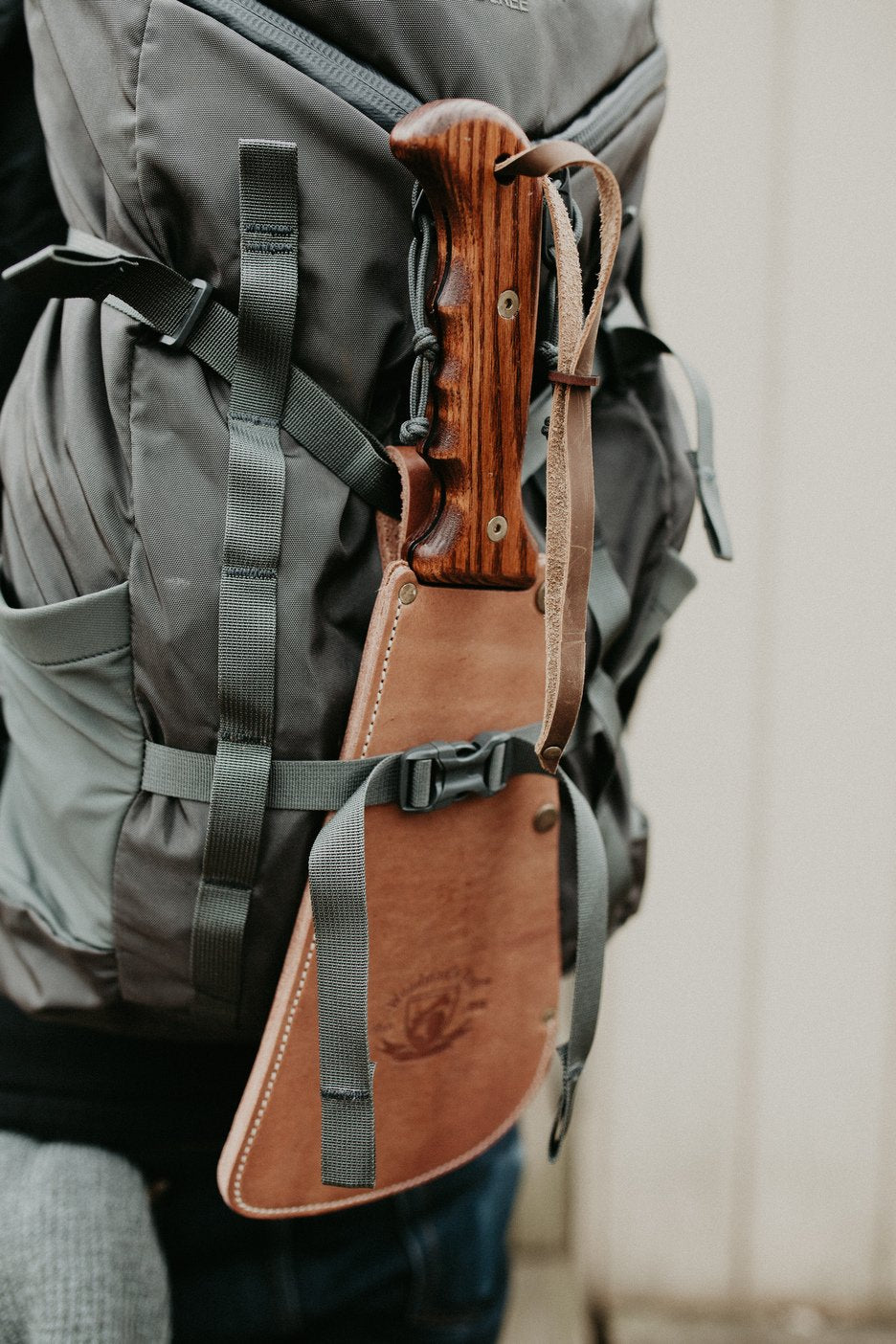 Wood-handle Woodman's Pal in its leather sheath strapped to a backpack