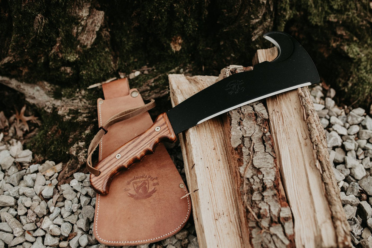 Wood-handle Woodman's Pal resting on its leather sheath on split firewood