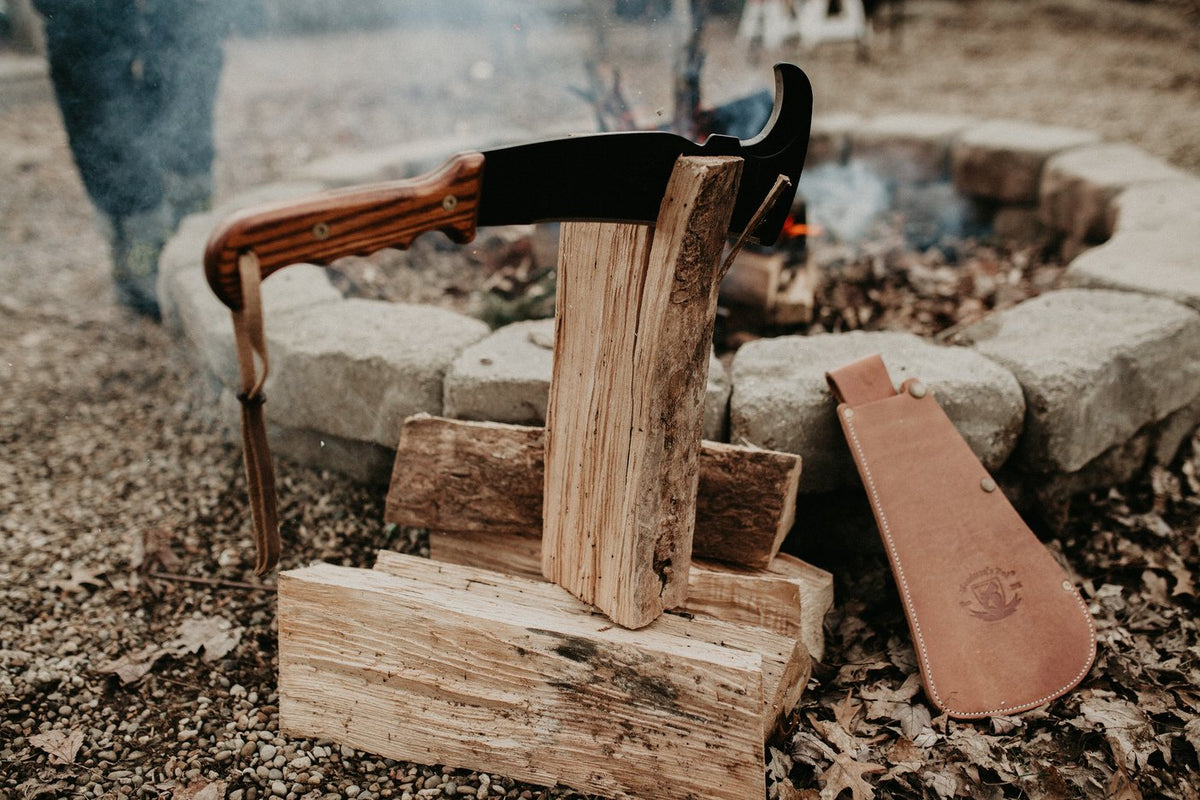 Wood-handle Woodman's Pal stuck in a log beside a stone fire pit