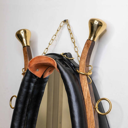Side angle showing thick padded black leather, solid brass hardware, and wooden frame of the horse collar mirror